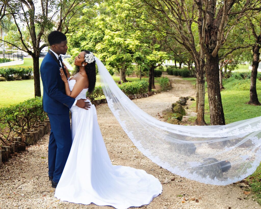 Bride and groom embracing on a garden path, veil flowing