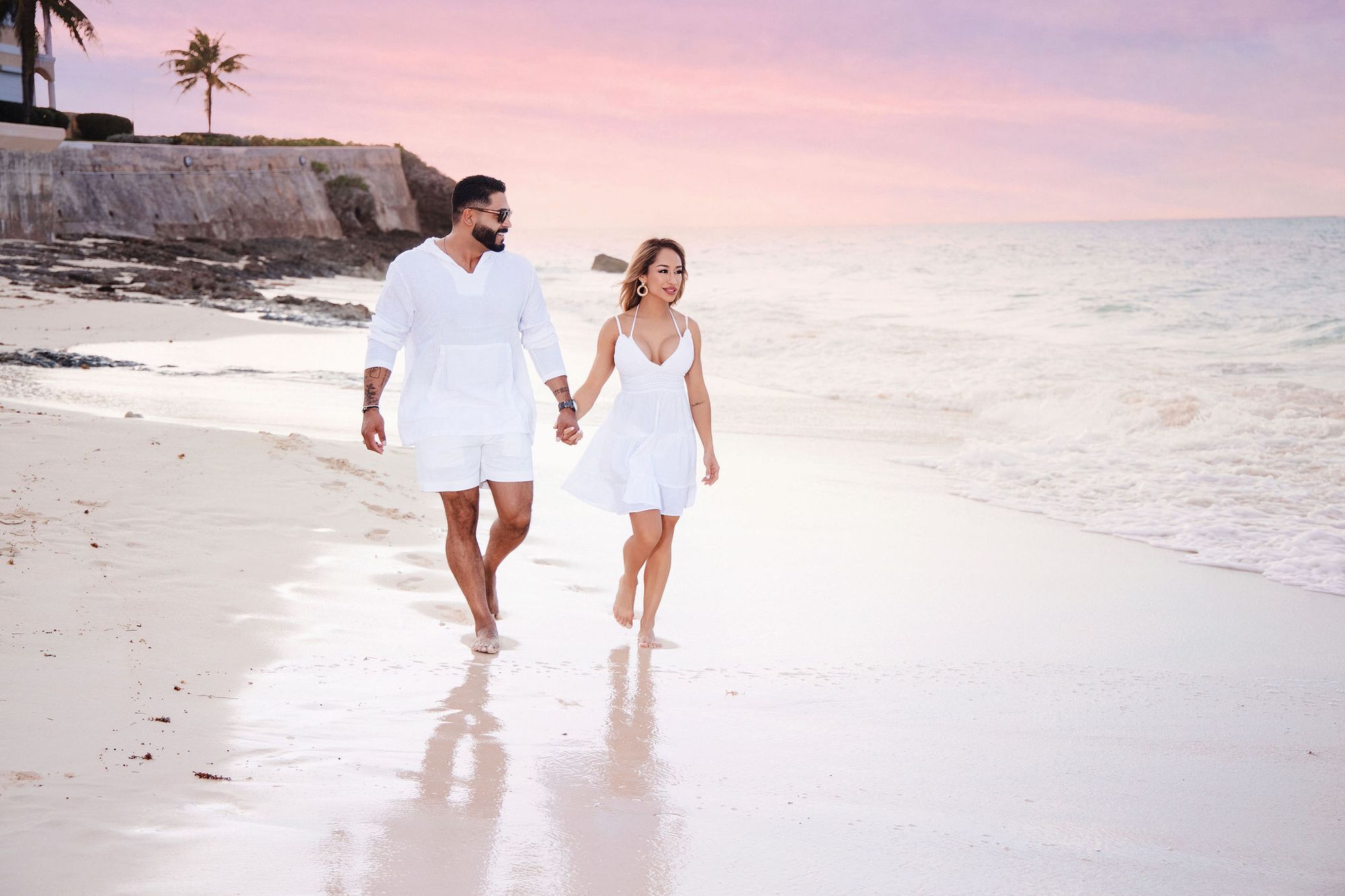 Couple walking the shoreline at sunset