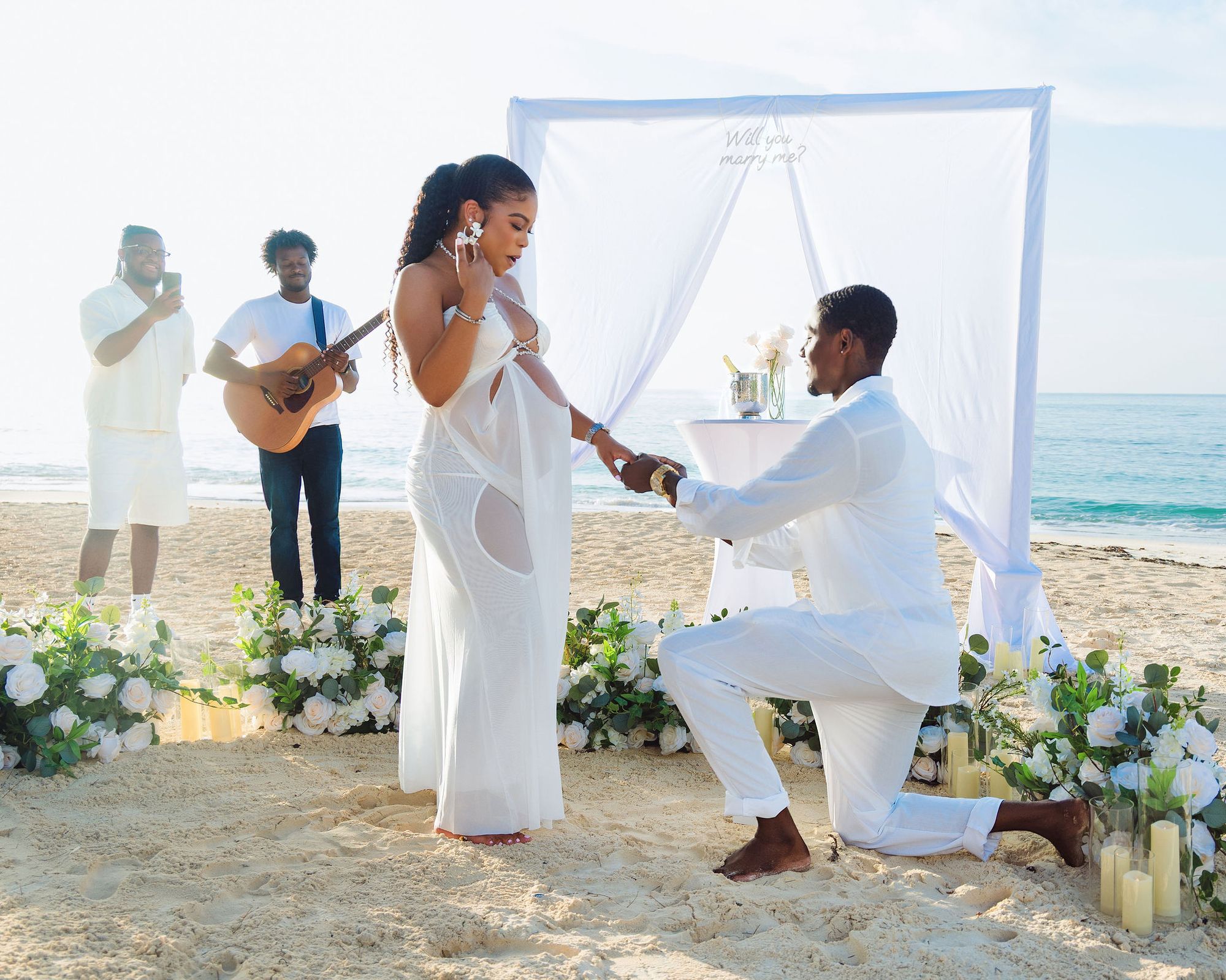 Beach proposal surrounded by white roses