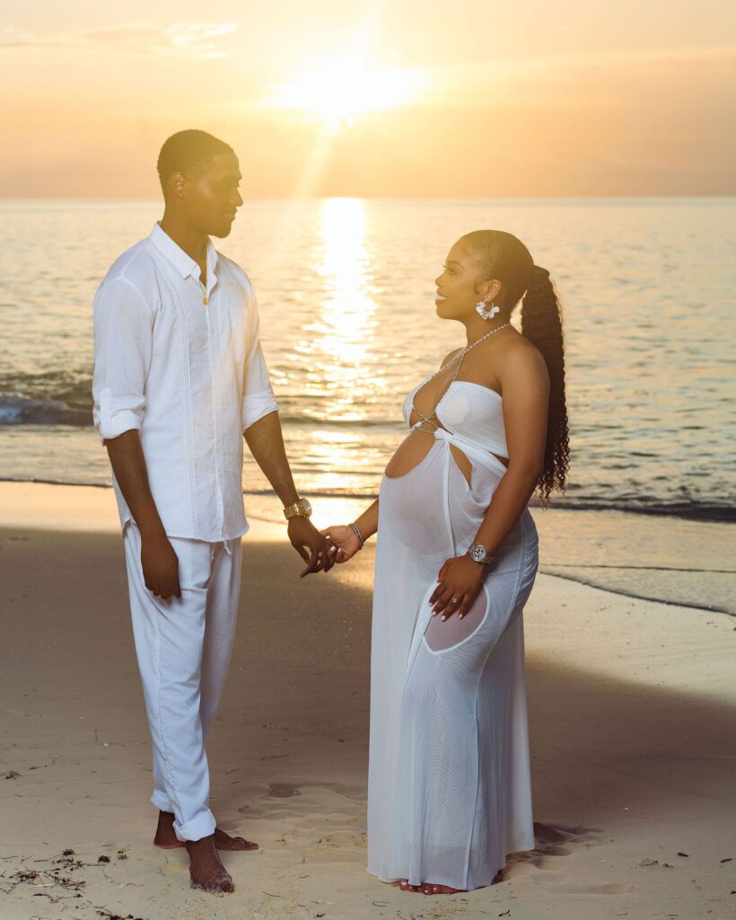 Expecting couple on the beach at sunset
